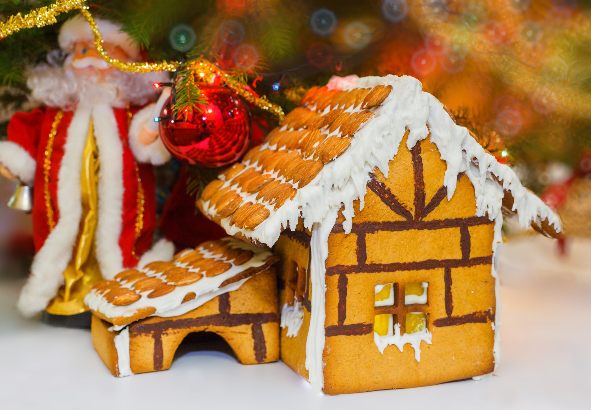 Christmas gingerbread house decoration on background of defocused christmas tree. Hand decorated.