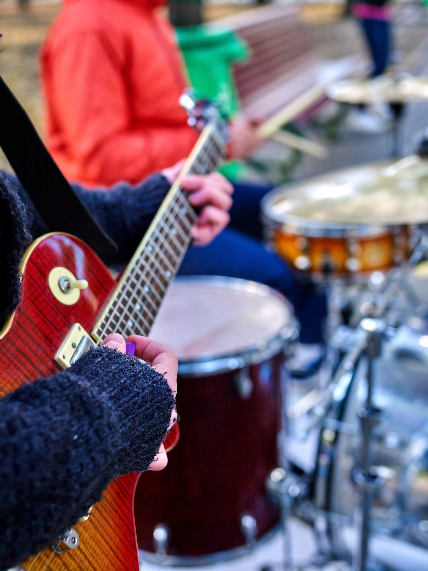 Music street performers on autumn outdoor. Middle section of body part. Hands with guitar on foreground.